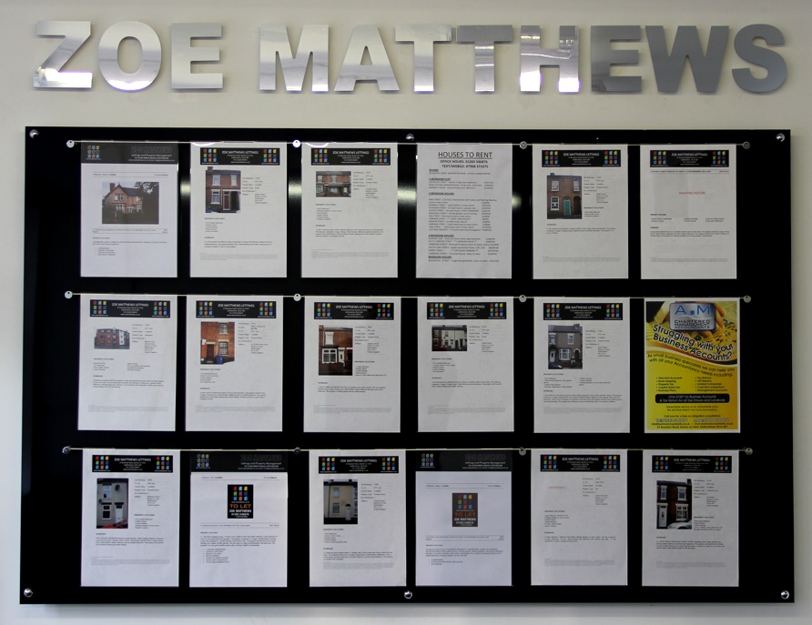 An acrylic hook-on poster holder display attached to the wall inside a shop. The display consists of three long steel bars, and eighteen A4 portrait pockets.
