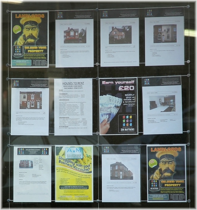 An acrylic hook-on poster holder display in a shop window. The display consists of three cables, six steel bars, and twelve A4 portrait pockets.